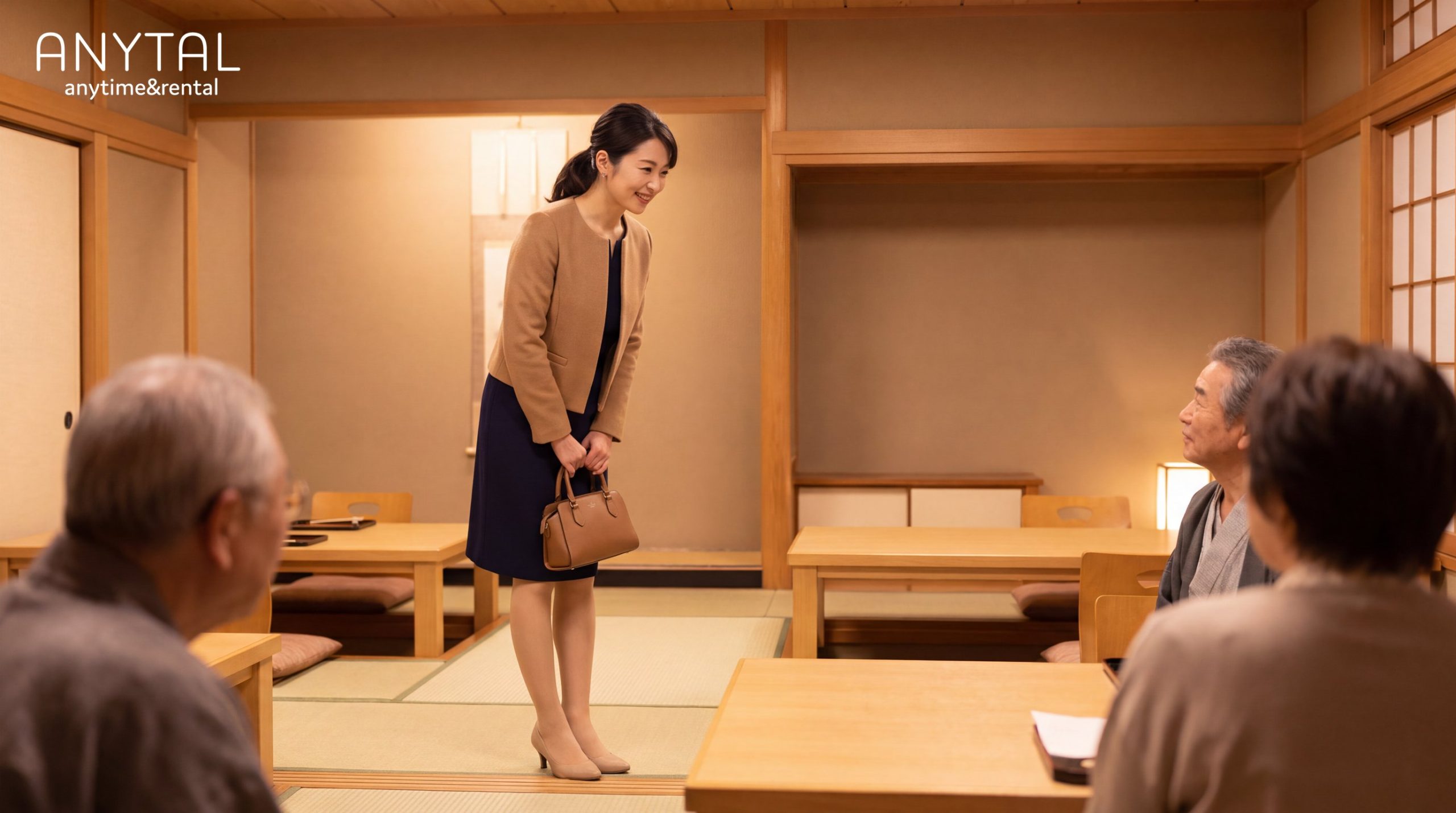 ベージュのジャケットとネイビーのワンピースを着て、和室で両家顔合わせの挨拶をする女性
